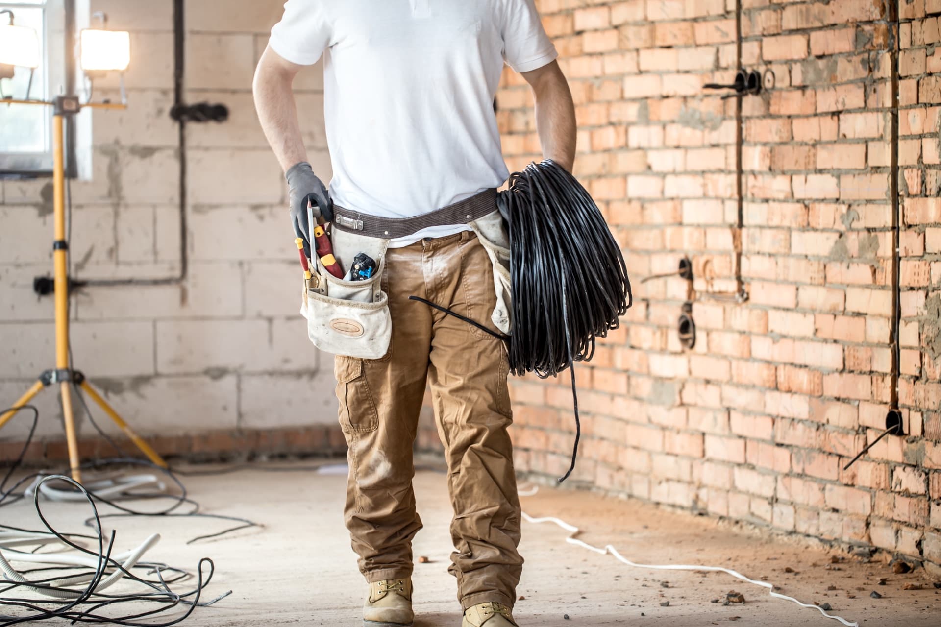 Licensed electrician carrying a wire spool on a commercial job